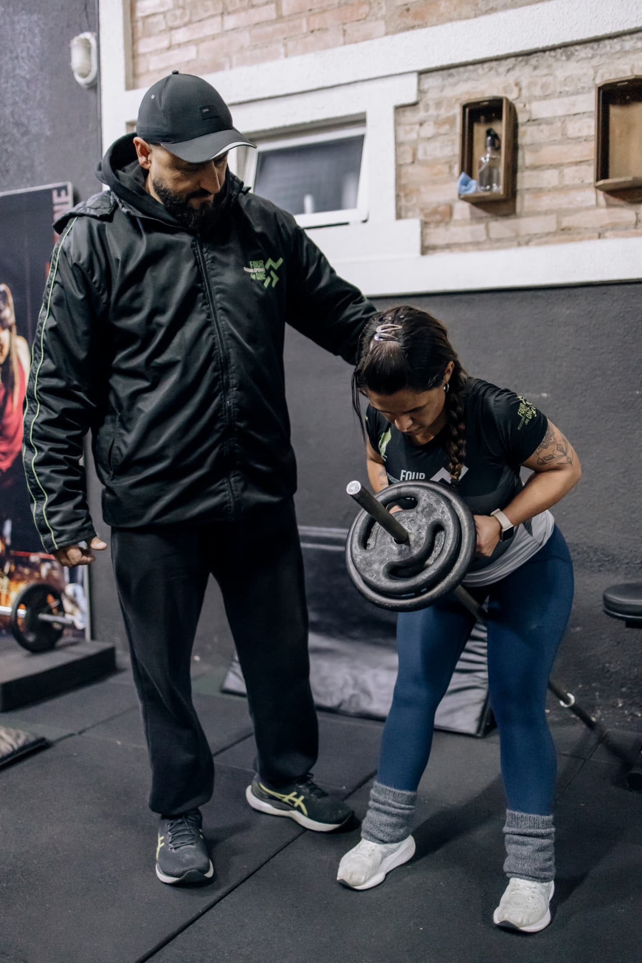 Professor acompanhando aluna em exercício com barra na Four One